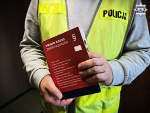 Policjant trzyma książkę Prawo karne zbiór przepisów.