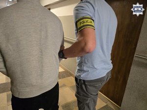 Nieumundurowany policjant doprowadza zatrzymanego.