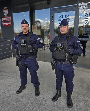 Dwaj policjanci stoją przed budynkiem.