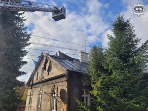 Ugaszony pożar w budynku - z boku widoczny wysięgnik strażacki z drabiną.