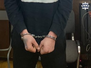 Ręce zatrzymanego mężczyzny w kajdankach.