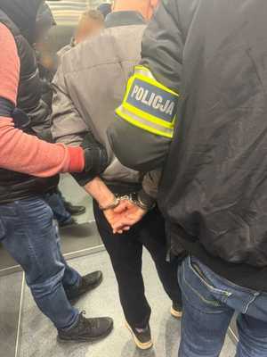 Zatrzymany prowadzony przez dwóch policjantów.