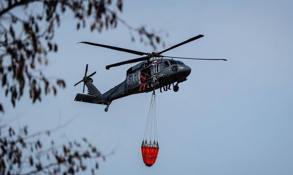 Śmigłowiec w locie z podczepionym zbiornikiem Bambi Bucket.