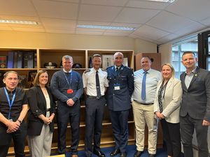 Grupa uczestników spotkania w siedzibie policji irlandzkiej w Dublinie pozuje wspólnie do zdjęcia. Wśród nich znajduje się funkcjonariusz polskiej Policji w umundurowaniu służbowym oraz przedstawiciele irlandzkiej Policji i Międzynarodowego Stowarzyszenia Policji  IPA.