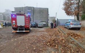 Wóz strażacki, radiowóz i samochody osobowe przy budynku, w którym wybuchł pożar.