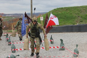 Funkcjonariusz podczas zawodów strzeleckich idzie trzymając z dwa worki.