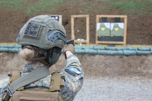 Odwrócona tyłem funkcjonariuszka mierzy do celu.