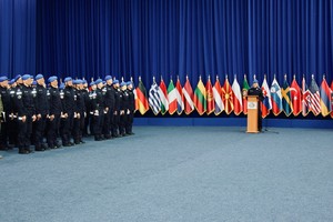 Funkcjonariusze na sali w szeregach. W głębi flagi państw.