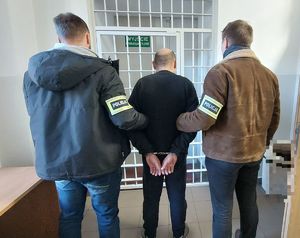 Dwaj policjanci prowadzą zatrzymanego.