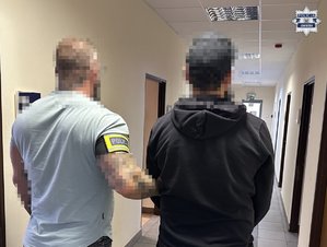 policjant stoi z zatrzymanym.