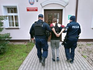 Dwaj policjanci prowadza zatrzymanego.