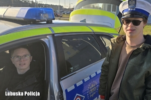 Jeden z chłopców siedzi za kierownica radiowozu, drugi stoi przy aucie.