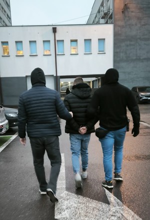 Policjanci prowadzą zatrzymanego.