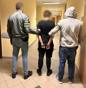 policjanci stoją z zatrzymanym.