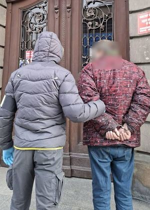 Nieumundurowany policjant prowadzi zatrzymanego.