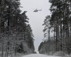 śmigłowiec lata nad lasem.