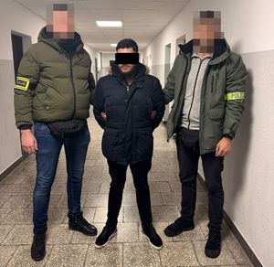 policjanci stoją z zatrzymanym.