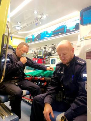 policjanci siedzą w karetce i oddychają dodatkowym tlenem.