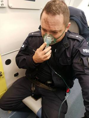 policjant siedzi w karetce i oddycha dodatkowym tlenem.