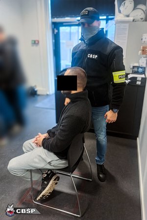 Policjant stoi przy zatrzymanym.