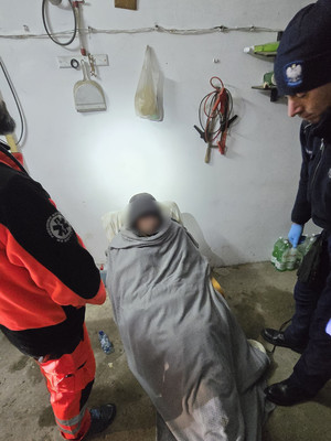 policjant okrywa kocem mężczyznę.