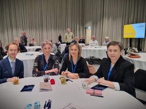 Kobity i mężczyzna siedzący przy stole.