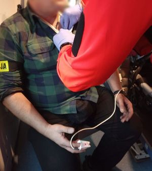 Ratownik udziela pomocy funkcjonariuszowi siedzącemu w karetce.