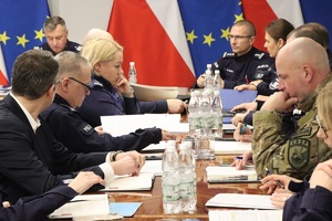 Uczestnicy spotkania siedzą przy owalnym stole.