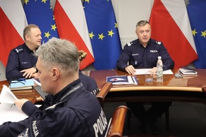 Uczestnicy spotkania siedzą przy owalnym stole.