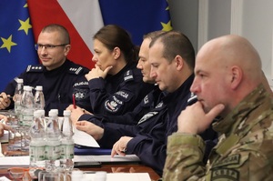 Uczestnicy spotkania siedzą przy owalnym stole.