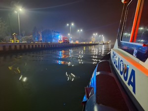 Bok łodzi policyjnej stojącej przy brzegu Martwej Wisły.
