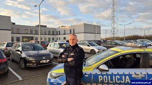Policjant stoi przy radiowozie.