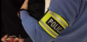 Policjant prowadzi zatrzymanego.