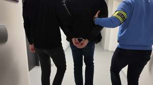 Policjanci prowadzą zatrzymanego.