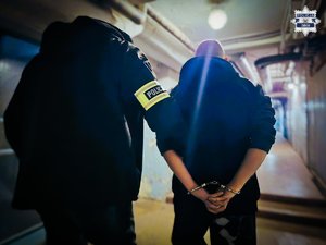 Nieumundurowany policjant prowadzi zatrzymanego.