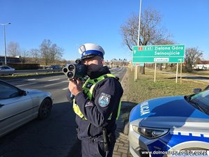 Policjant ruchu drogowego z fotoradarem w ręku.