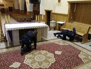 Dwaj policjanci przeszukujący wnętrze kościoła w poszukiwaniu bomby.