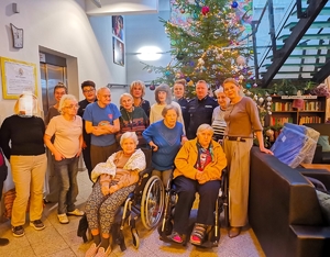 Policjanci z Biura Prewencji KGP podczas spotkania z podopiecznymi Centrum Alzheimera w Warszawie, w tle za nimi choinka świąteczna.