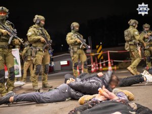 Zdjęcie przedstawia funkcjonariuszy służb specjalnych oraz leżących na ziemi mężczyzn.