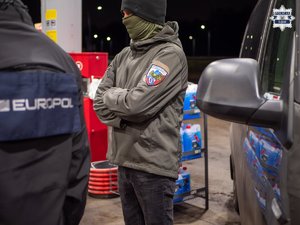 Zdjęcie przedstawia dwóch funkcjonariuszy stojących obok samochodu.