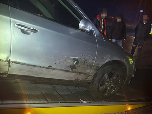 Auto, które wjechało do rowu na lawecie. Obok widać trzy osoby.