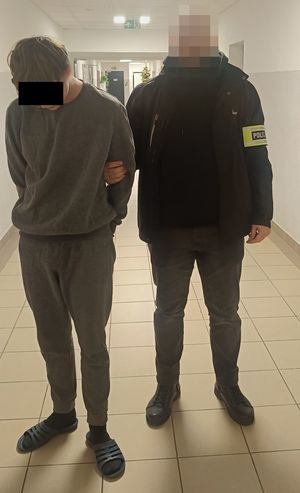 Policjant prowadzi zatrzymanego.