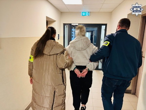 policjanci prowadzą zatrzymaną.