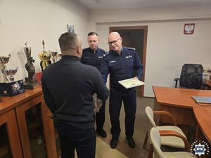 Policjanci wręczają podziękowania.