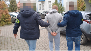 Dwaj funkcjonariusze prowadzą zatrzymanego.