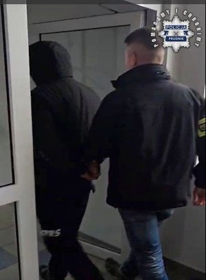 Nieumundurowany policjant prowadzi zatrzymanego.