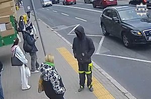 Stopklatka z nagrania monitoringu. Zatrzymany mężczyzna stoi na przystanku razem z innymi ludźmi.