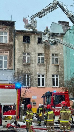 Pożar budynku, obok którego pracują służby m.in. straż pożarna.