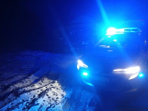 Pora nocna - policyjny radiowóz z włączoną sygnalizacją świetlną.