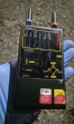 widać wagę, narkotyki w woreczku foliowym i zgrzewnicę. białe kryształki w worku foliowym, następnie dłoń w gumowej rękawiczce przekłada worki z marihuaną w kartonie. radiowóz, policjanta, który zakłada kajdanki zatrzymanemu, który leży na ziemi, następnie widok na pomieszczenie, w którym są paczki i worki z narkotykami, leżący luźno susz i półki na których są różne przedmioty. W pomieszczeniu panuje rozgardiasz.